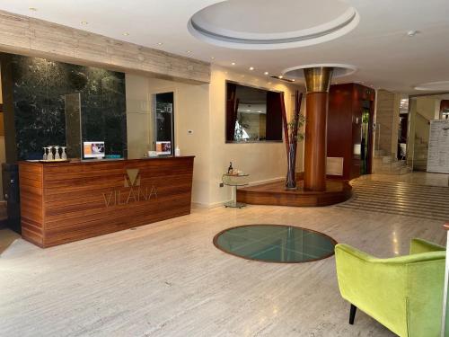 巴塞罗那Vilana Hotel Boutique的大堂设有玻璃桌和绿色椅子