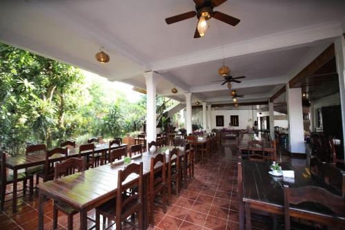 琅勃拉邦旺萨维饭店的餐厅配有桌椅和吊扇