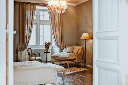 CrazannesChâteau de Crazannes的一间卧室配有一张床、一把椅子和一个吊灯。