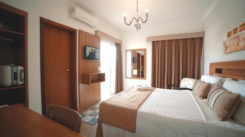 卡舒埃拉保利斯塔Hotel Água Viva - By UP Hotel的酒店客房设有一张大床和一张桌子。