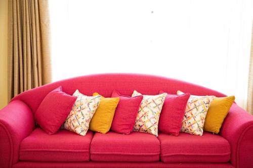 纳纽基Cottage in Nanyuki, Maiyan; Swara Ranch #28的粉红色的沙发上配有色彩缤纷的枕头
