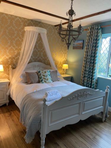 基尔基Sycamore Lodge的一间卧室配有一张带天蓬的白色床