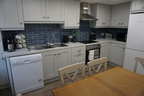 多尼戈尔Whitehorse House的厨房配有白色橱柜、水槽和炉灶。
