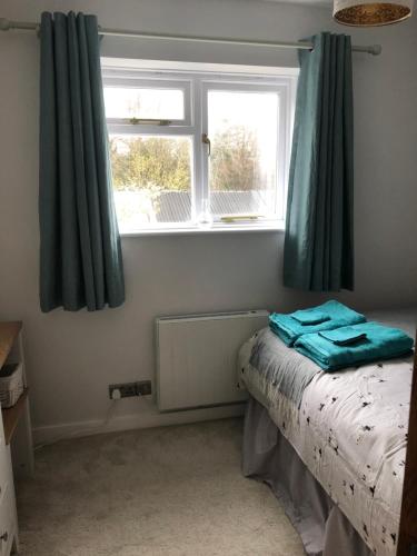 比明斯特Chapel View Cottage的一间卧室配有床和蓝色窗帘的窗户