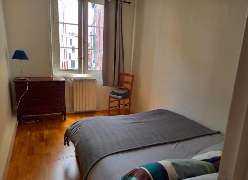 巴约讷Appartement au coeur de Bayonne sur les remparts的一间卧室配有一张床、一张书桌和一个窗户。