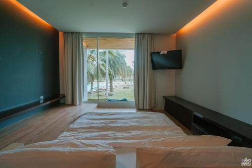 罗勇奥哈纳度假村及餐厅的一间卧室设有一张床和一个大窗户