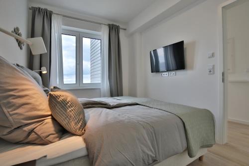 宁多夫Strandperle Ostsee Suite 4的卧室配有一张床铺,墙上配有电视