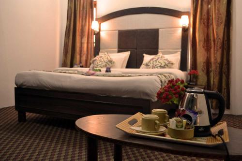 斯利那加Hotel Al Azrah的酒店客房,配有一张床铺和一张桌子,并备有咖啡托盘