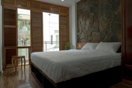 胡志明市Homestay TITO的一间卧室设有一张大床和石墙