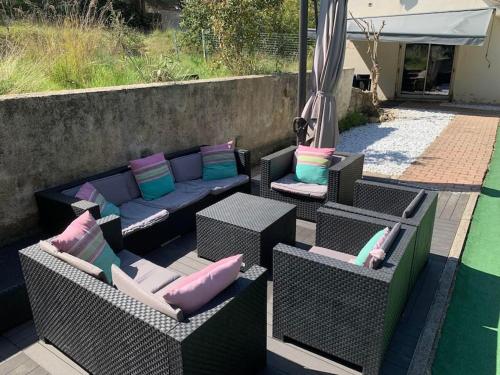 Saint-Mitre-les-RempartsL'Olivier的庭院设有藤椅和带枕头的沙发。