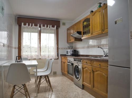 阿维莱斯La Villa De Lore, Piso Completo Apto 6 Personas的厨房配有木制橱柜、桌子和洗碗机。