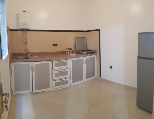 胡塞马appartement boukidan的空厨房配有白色橱柜和冰箱