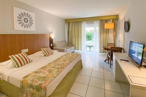 布希奥斯Búzios Beach Resort的酒店客房配有一张床、一张书桌和一台电视。