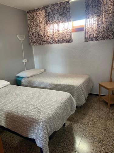 洛斯克里斯蒂亚诺斯Canary Islands Apt的客房设有两张床、一张桌子和一盏灯。
