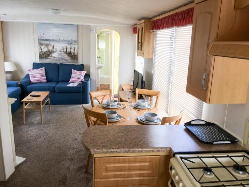 斯凯格内斯Sea Breeze at Winthorpe Skegness的厨房以及带蓝色沙发的客厅。