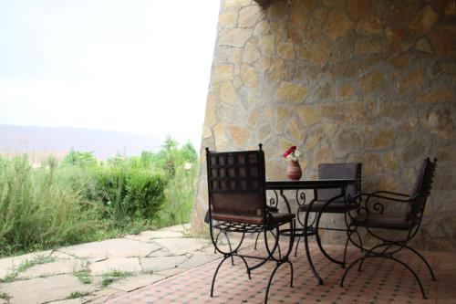 廷吉尔AZIGHAME Complexe Touristique的一张桌子和椅子,坐在石墙旁