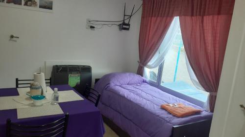 乌斯怀亚Mono ambiente el mirador的一间卧室配有紫色的床、桌子和窗户。