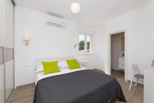 苏提万Apartment Reful的白色卧室配有一张带绿色枕头的大床