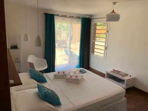 布拉伊POÉ CÔTÉ LAGON的一间卧室配有一张带蓝色枕头的床和一扇窗户。