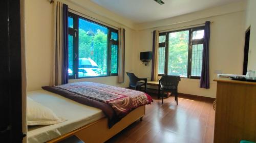 卡索尔The Royal Orchard Kasol的卧室配有一张床、一张书桌和窗户。
