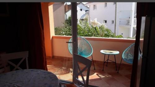 蒂瓦特Apartmani Tanja的阳台配有两把椅子和一张桌子,还有一个窗户。