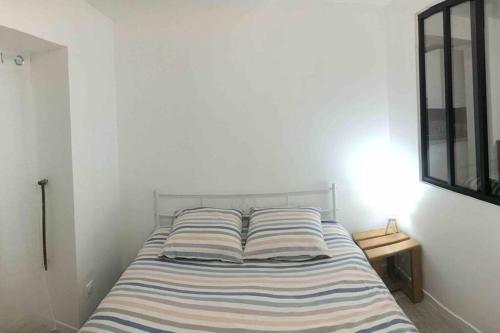 Creuzier-le-NeufLogement indépendant Piscine et Jardin的白色卧室内的带条纹枕头的床
