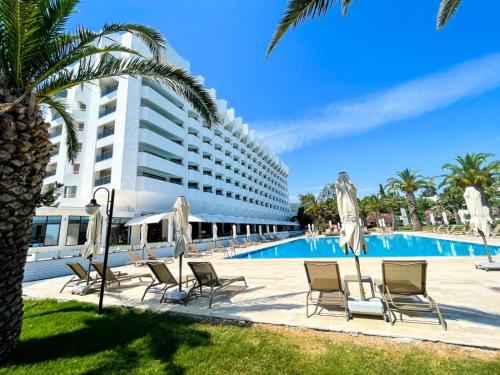 伊兹密尔Club Beyy Resort Hotel - Ultra All Inclusive的酒店游泳池设有椅子,大楼