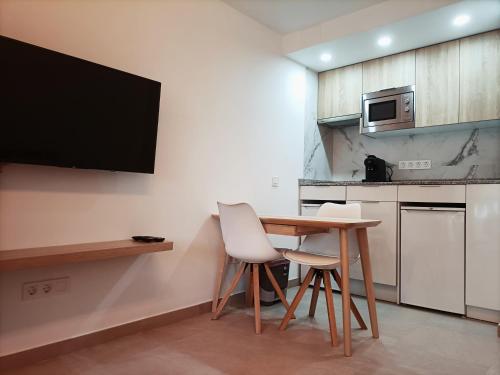 多列毛利诺斯Joan Miró Luxury Torremolinos的厨房配有桌子和两把椅子以及电视。