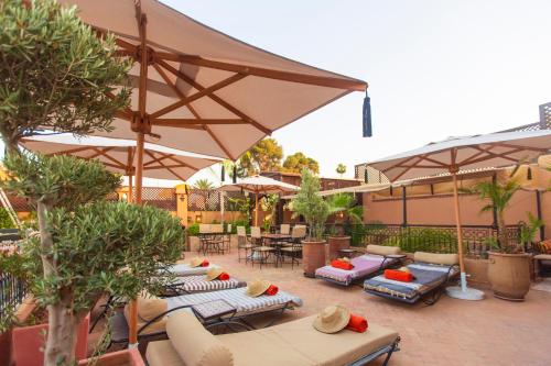 马拉喀什Riad Anya & SPA的一个带遮阳伞和躺椅及桌子的庭院