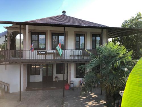 古达乌塔Vse Dlya Vas Guest House的房屋设有两面旗的阳台