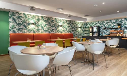 奥斯陆松恩酒店的餐厅设有桌子和白色椅子,并装饰有绿色壁纸。