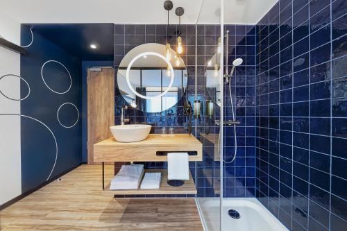 杜塞尔多夫H2 Hotel Düsseldorf City的蓝色瓷砖浴室设有水槽和镜子