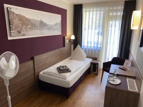 科赫姆Altes Winzerhaus的酒店客房配有一张床、一张书桌和风扇