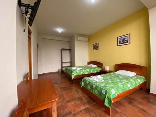 塔拉波托Monteverde Tarapoto "Eco-Friendly"的一间卧室配有两张床、一张桌子和一张桌子
