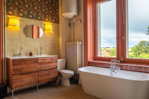 Buzançais薄荷璐堡酒店的带浴缸、卫生间和窗户的浴室
