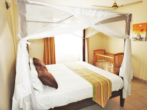 迪亚尼海滩Galu Gardens Apartments Diani Beach的一间卧室配有一张带一张婴儿床的天蓬床