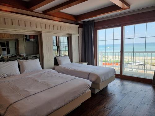 襄阳郡Benikea Hotel Mountain & Ocean Yangyang的酒店客房设有两张床和大窗户。