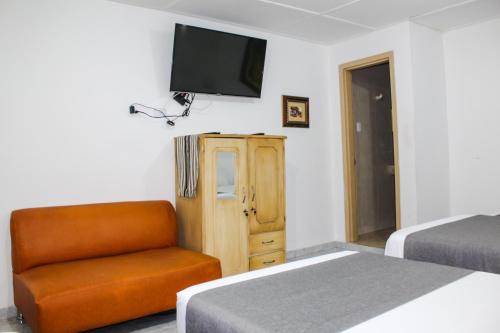 巴兰基亚Hotel Poblado Suite的一间卧室配有两张床、一把椅子和一台平面电视。