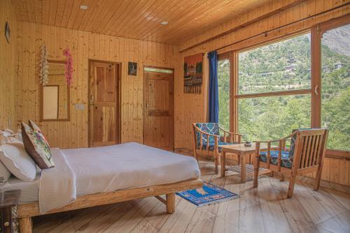 本贾尔Sharda Resort-Tirthan Valley的一间卧室配有一张床、一张桌子和一个窗户。