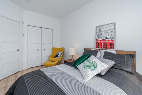 魁北克市The Urban Oasis - Old Quebec - Gym - AC - Indoor Parking的一间卧室配有一张床和一张黄色椅子