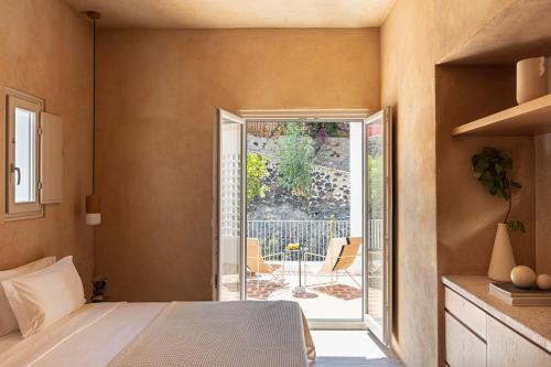 费拉Ethos Vegan Suites的一间卧室设有一张床,并设有一个通往庭院的开放式门。