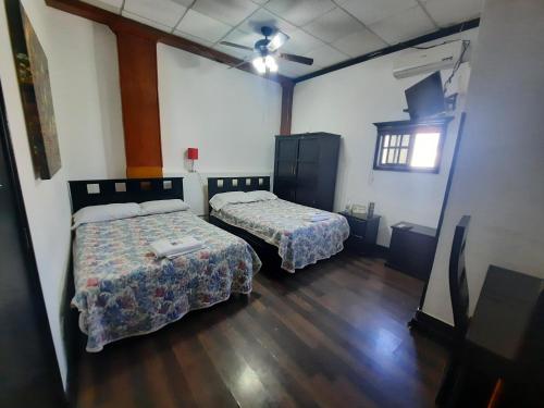 LinaresGarcias Suites y Hotel的铺有木地板的客房内的两张床