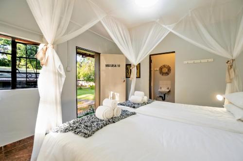 维多利亚瀑布Shoestrings Backpackers Lodge Vic Falls的卧室配有一张白色窗帘的大床