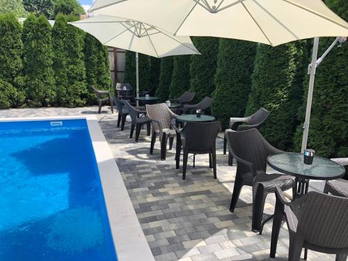 欧罗什哈佐布里尔奥罗索哈札酒店的游泳池旁带桌子和遮阳伞的天井