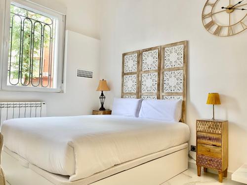 马德里Charming Madrid Studio - Largas Estancias的白色卧室设有一张大床和时钟