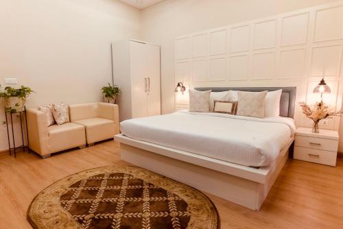 阿姆利则银叶公寓的卧室配有一张白色的大床和一张沙发。