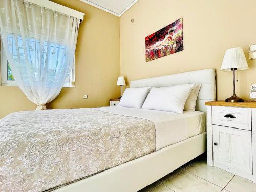 干尼亚Christina_Apt的卧室配有白色的床和窗户。