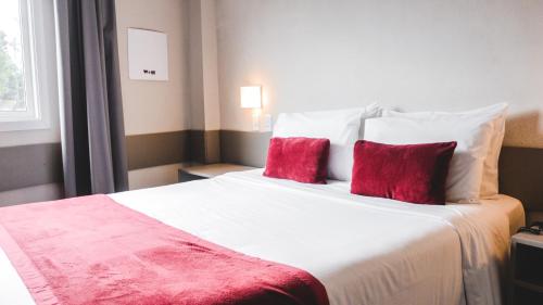 圣利奥波尔杜Work Hotel São Leopoldo的卧室配有带红色枕头的大型白色床