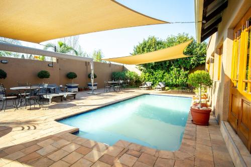 博克斯堡非洲精品酒店​​O.坦博的一个带遮阳伞的庭院内的游泳池