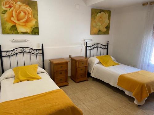 卡拉塔尤德Pensión Santa Rita的一间卧室配有两张带黄床单和绘画的床